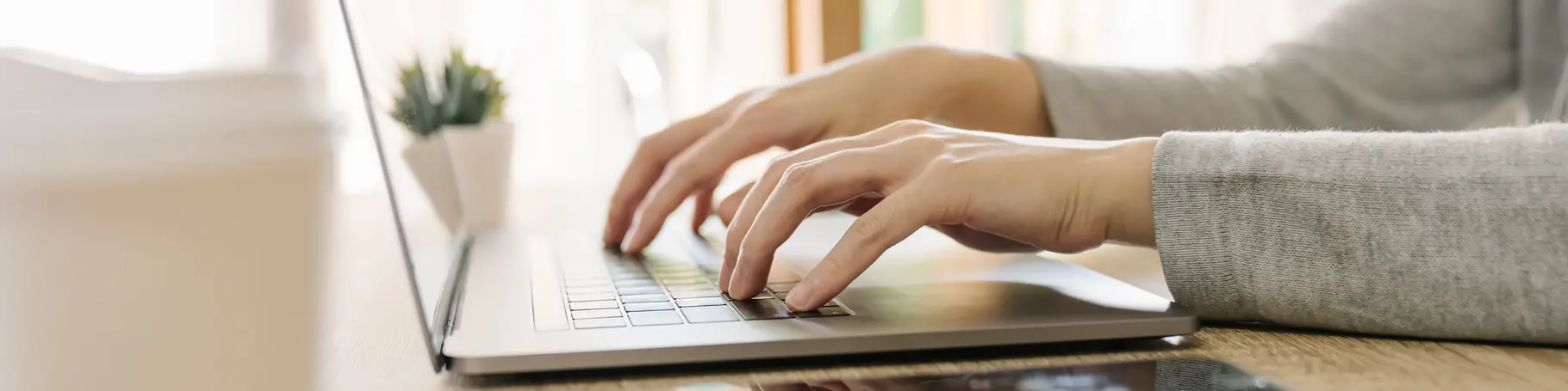 Business woman hand typing laptop computer on wooden table