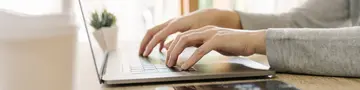Business woman hand typing laptop computer on wooden table