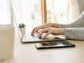 Business woman hand typing laptop computer on wooden table
