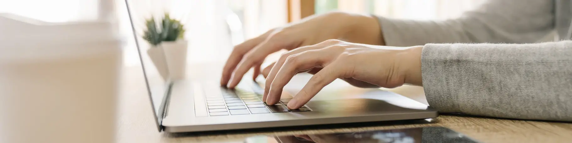 Business woman hand typing laptop computer on wooden table
