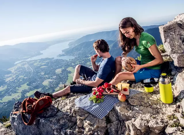 im Urlaub am Tegernsee machen Wanderer eine Brotzeit mit Blick auf den Tegernsee