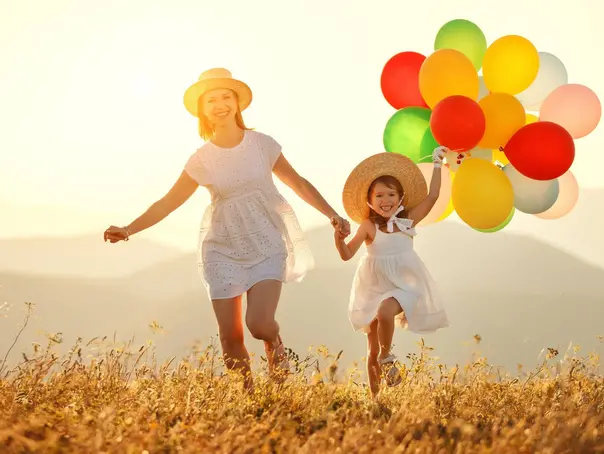 happy family mother and child daughter with balloons at sunset in summer