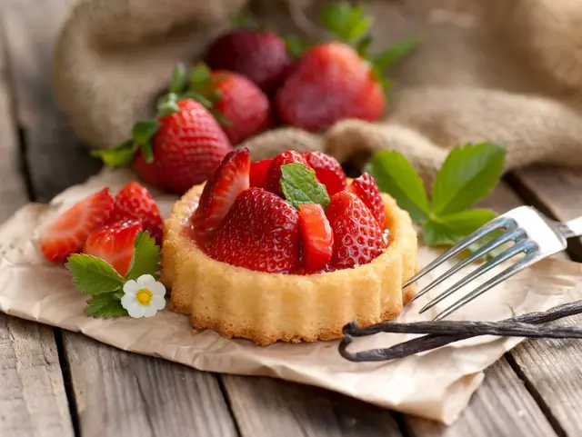 Kleiner hausgemachter Erdbeerkuchen mit frischen Erdbeeren auf einem Teller.