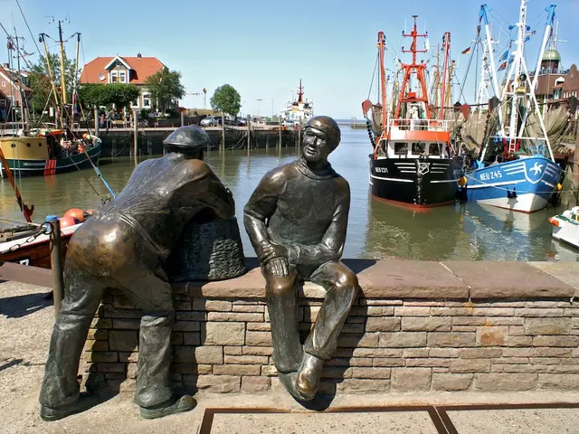 Zwei Fischer aus Metall blicken auf den Hafen Neuharlingersieler an der Nordsee hinaus aufs Meer.