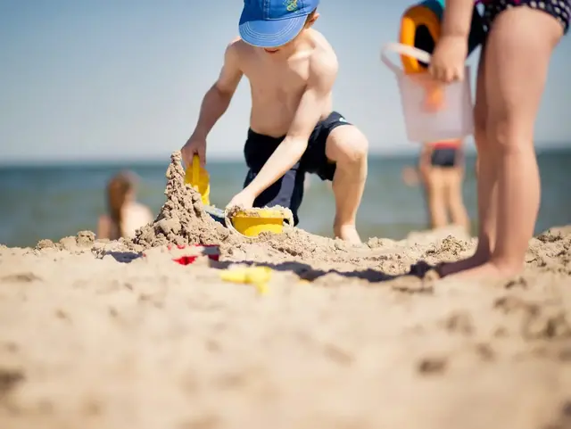 Buddelspaß am Strand – Familienurlaub auf Fehmarn Ein Kind buddelt im Sand am Meer während des Familienurlaubs auf Fehmarn.