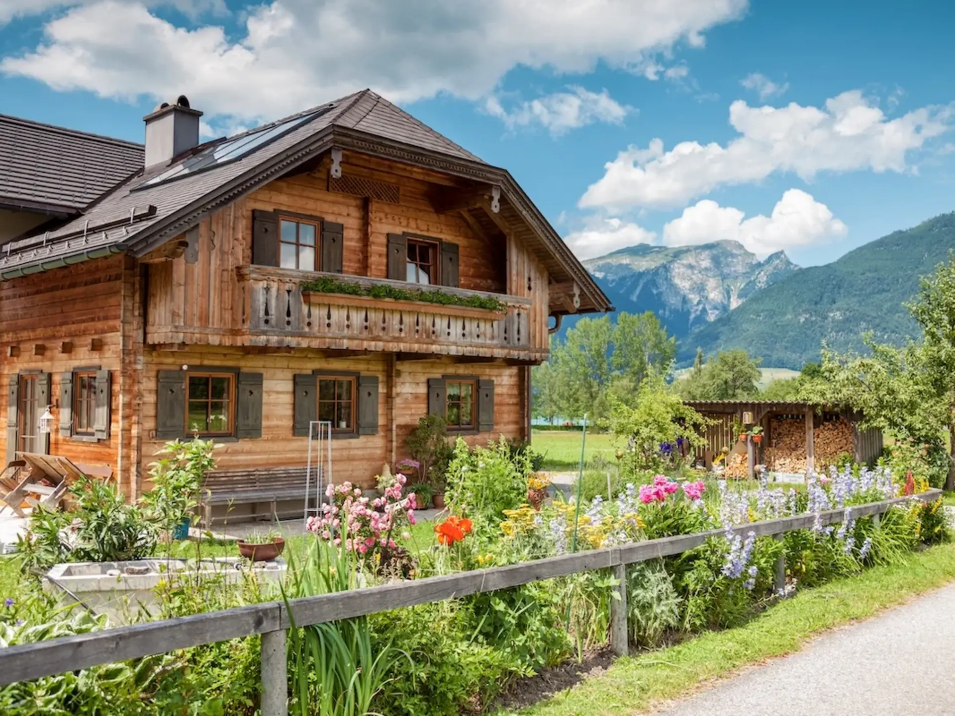 Traditionelles Holzhaus im Alpenstil steht auf einem Bauernhof inmitten grüner Berglandschaft – typisches Ferienhaus auf dem Land für naturnahen Urlaub in den Bergen. 
