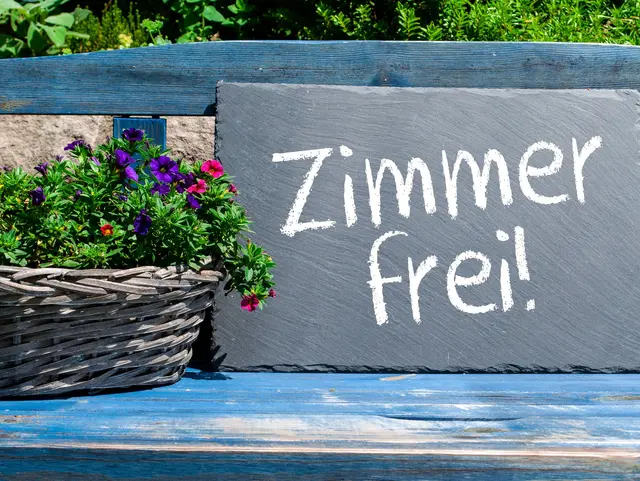 Blaue Holzbank mit Kreidetafel und Zimmer frei