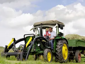 Bei einem Urlaub auf dem Bauernhof in Thüringen können Kinder auf dem Traktor mitfahren.