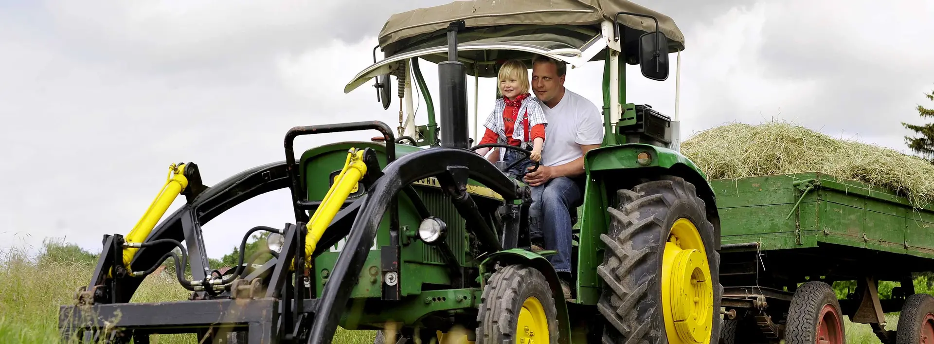 Bei einem Urlaub auf dem Bauernhof in Thüringen können Kinder auf dem Traktor mitfahren.