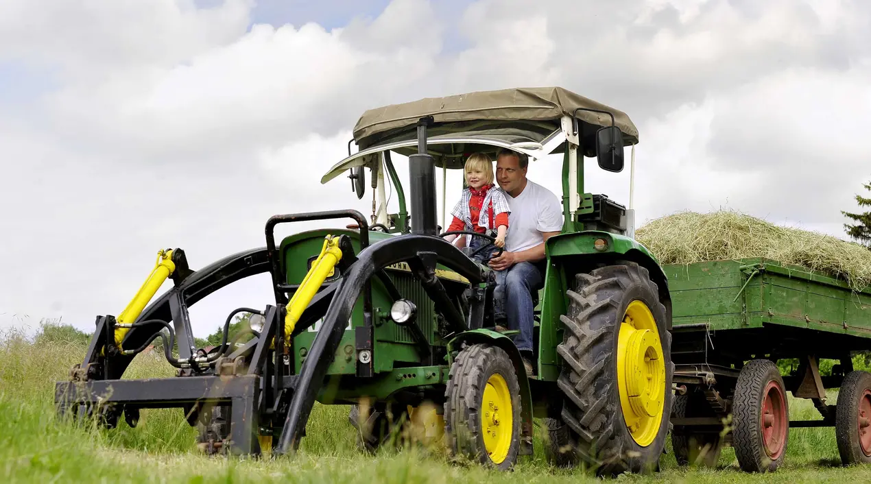 Bei einem Urlaub auf dem Bauernhof in Thüringen können Kinder auf dem Traktor mitfahren.