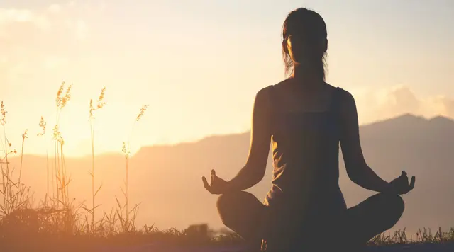 Person meditiert in der Natur bei Sonnenuntergang