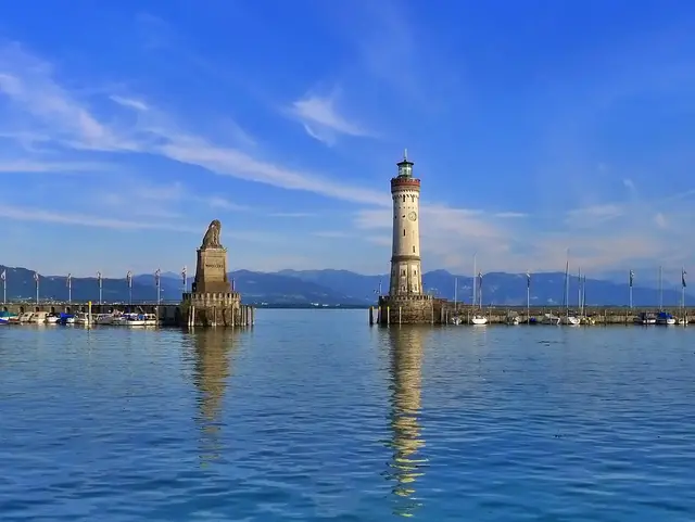 Hafeneinfahrt in Lindau am Bodensee - © Pixabay.de, Die Stadt Lindau liegt im bayerischen Teil vom Bodensee. An der Hafeneinfahrt stehen die Statue des Bayerischen Löwen und der steinerne Lindauer Leuchtturm mit Blick auf den See und die Berge.