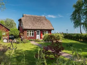 Kleines Haus mit Reetdach umgeben von großem Garten. 