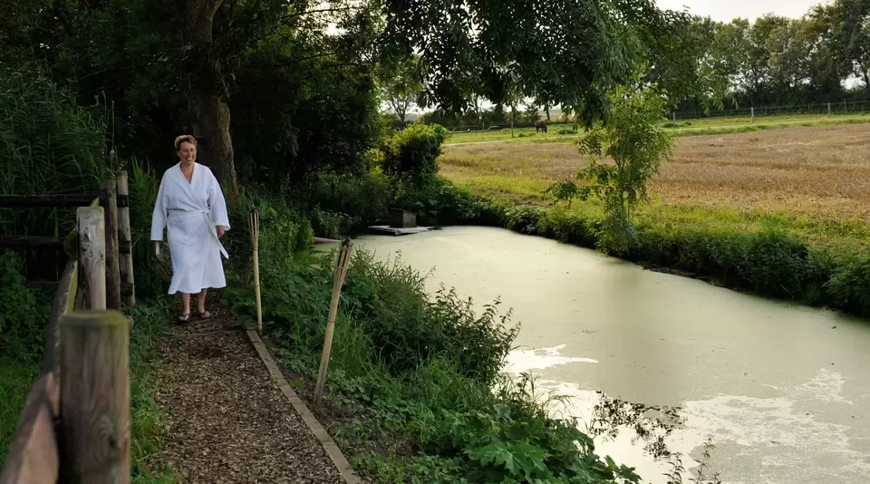 Frau läuft zu Fluss im Bademantel