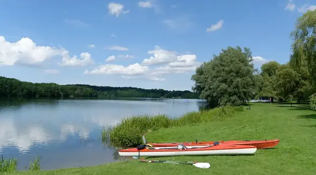 Zwei rote Seekajaks liegen am Ufer des Plönersees während einer Pause beim Kajakfahren in der Holsteinischen Schweiz. 