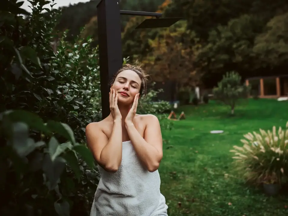 Wellnessurlaub auf dem Land – Entspannung nach der Sauna im Garten - © Halfpoint, AdobeStock Frau entspannt im Garten nach einem Saunagang während eines Wellnessurlaubs auf dem Land