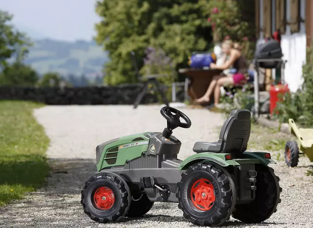 auf dem Kinderbauernhof in Bayern mit dem Kindertraktor bei der Hofarbeot helfen