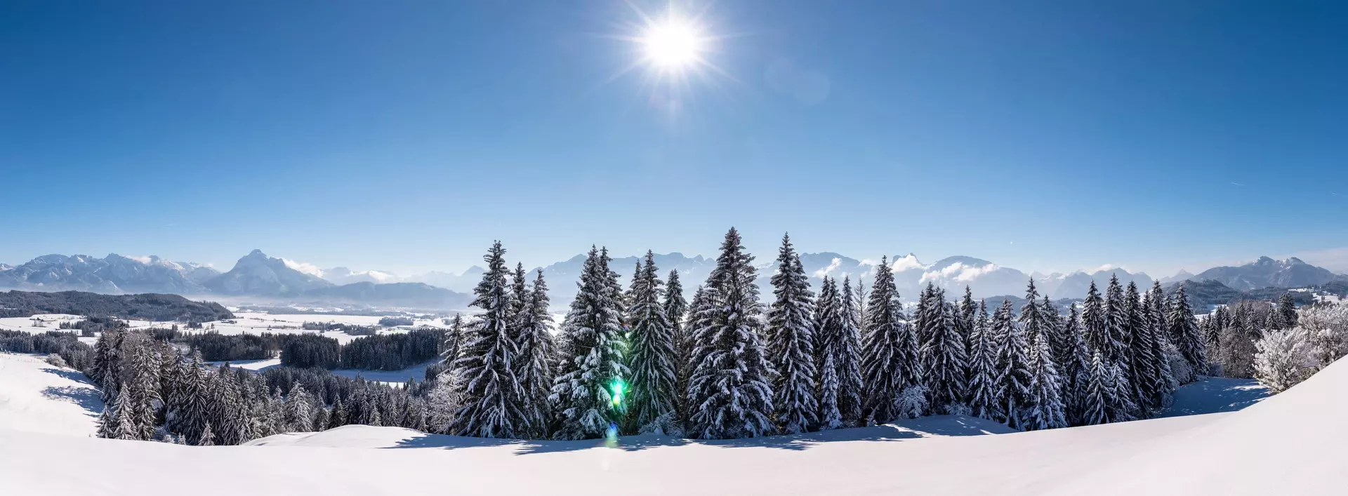 Panorama Sonne im Winter in den Bergen in Bayern und blauer Himmel