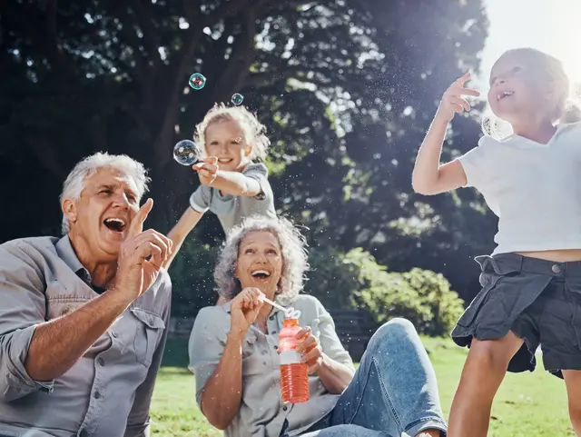 Grandparents, bubbles and children play in park happy together f Grandparents, bubbles and children play in park happy together for fun, joy and outdoor happiness. Retired, smile and excited elderly senior couple, girl grandkids and love playing outside in nature.