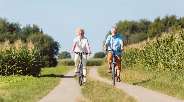 Ein älteres Ehepaar fährt mit dem Fahrrad über das Land. 