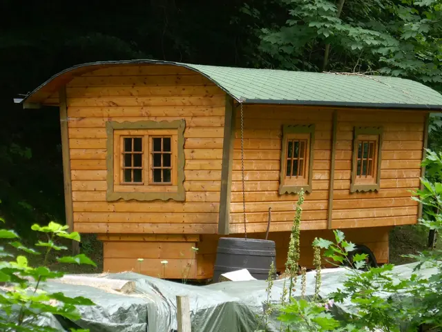 Rustikaler Holz-Schäferwagen steht im Grünen in ländlicher Umgebung