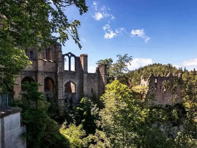 Kloster- und Burgruine auf einem Felsen umgeben von Wald und Felsenlandschaft