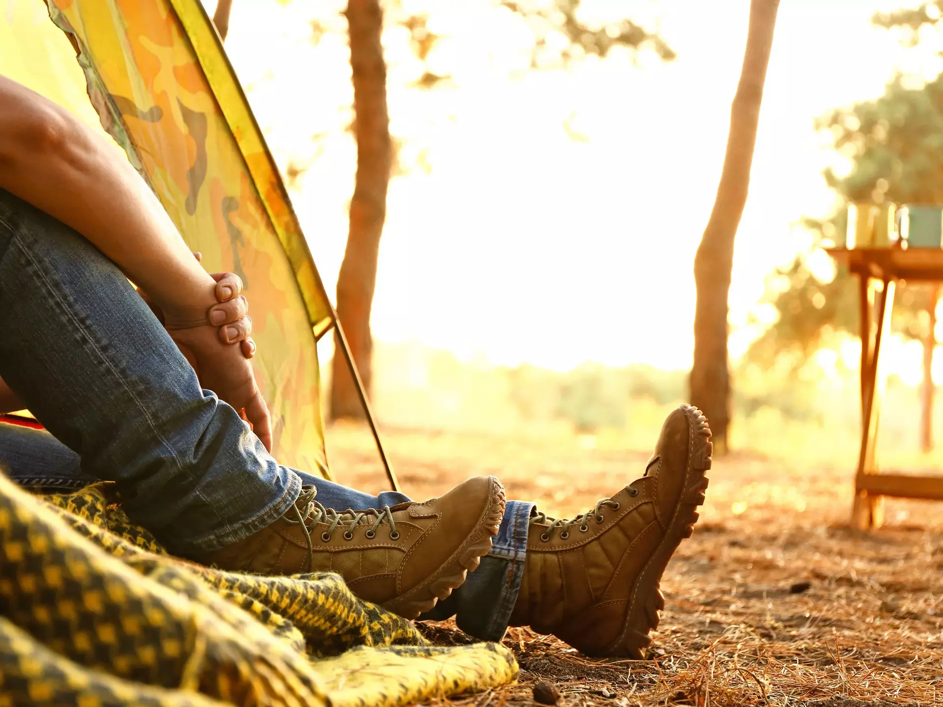 Junger Mann sitzt beim Camping am Zelt im Wald