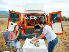 Zwei Frauen vor ihrem Van beim Camping auf dem Land 