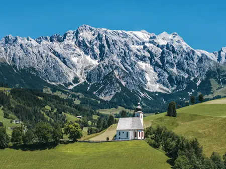 Blau-türkiser Bergsee im Herbst mit Silberdistel im Vordergrund.