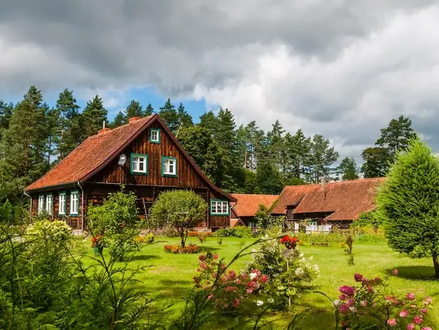 Traditioneller Bauernhof im Grünen – Urlaub auf dem Land erleben - © majonit, adobe stock Traditioneller Bauernhof mit Holzgebäuden, Garten und Wiesen in ländlicher Umgebung