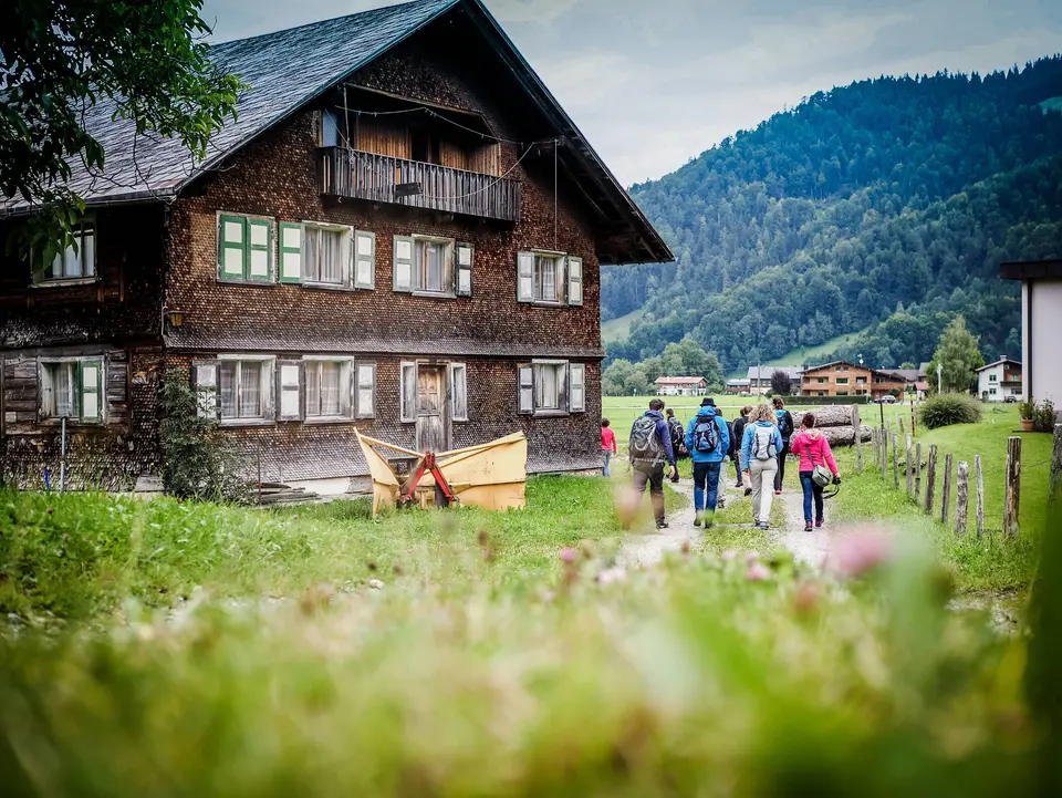 group of friends going for a hike in nature and walking through a village by passing a wooden old house