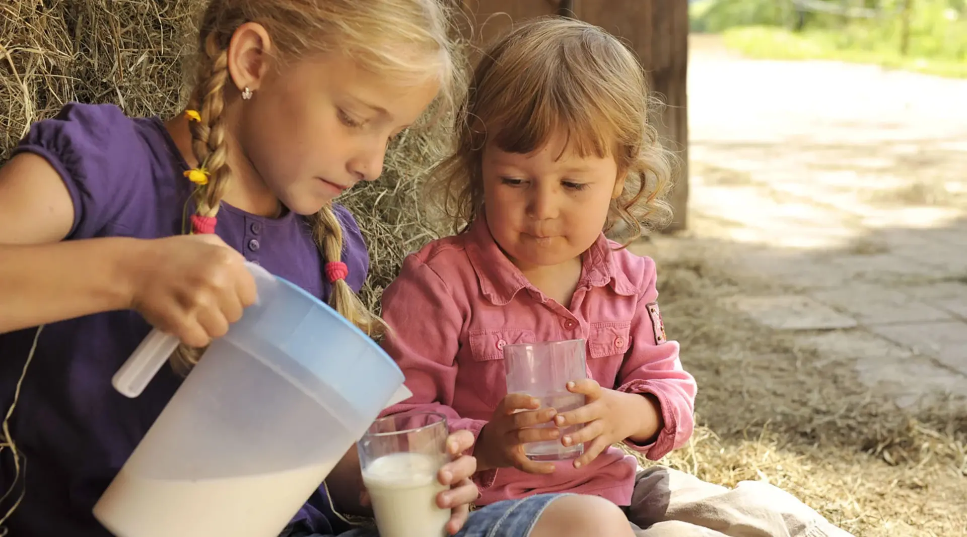 Kinder trinken frische Milch im Urlaub auf dem Bauernhof