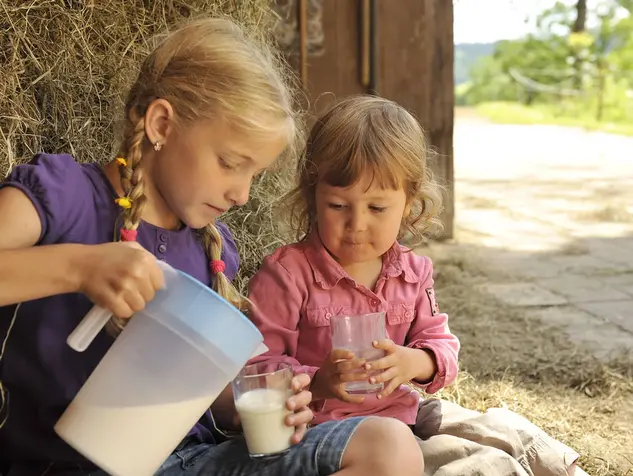 Kinder trinken frische Milch im Urlaub auf dem Bauernhof