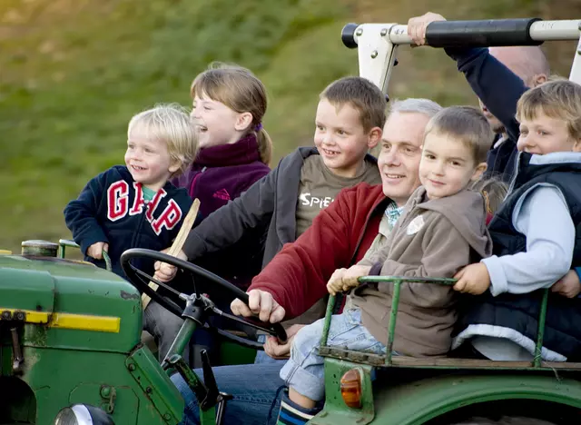 im Urlaub auf dem Kinderbauernhof eine Traktorfahrt mit dem Bauern machen