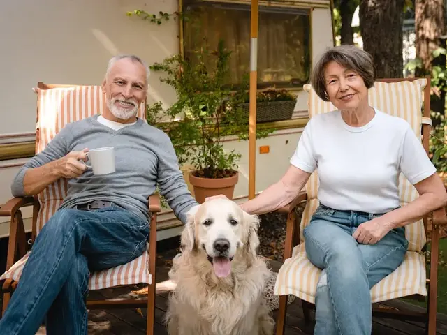 Urlaub mit Hund auf dem Land – Hundefreundliche Gastgeber - © InsideCreativeHouse, adobe stock Gastgeberpaar sitzt im Garten neben einem Hund