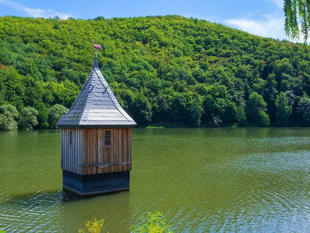 Historischer Kirchturm von Nieder-Werbe im Wasser des Edersee-Vorstaubeckens, umgeben von grünen, bewaldeten Hügeln.