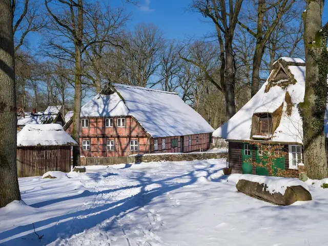 Ortsbild Wilsede im Winter Lüneburger Heide mit schneebedecktem Boden und Dächern.