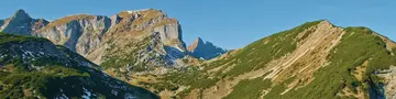 Blau-türkiser Bergsee im Herbst mit Silberdistel im Vordergrund.