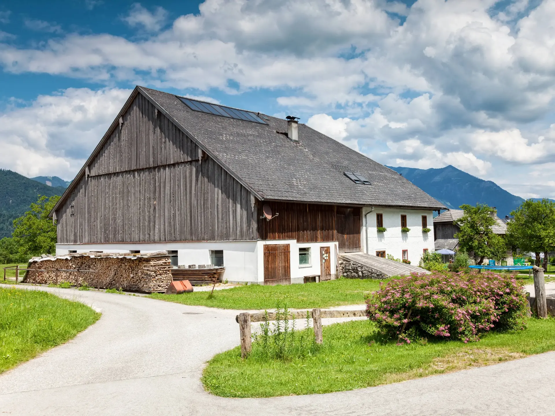 Traditionelles Bauernhaus in grüner Alpenlandschaft als Motiv für Urlaub auf dem Bergbauernhof.