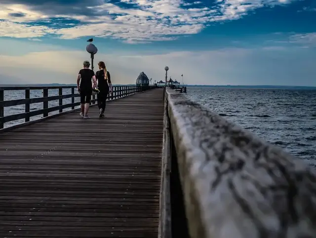 Zwei Personen laufen über den Steg von Grömitz hinaus in Richtung Ostsee.