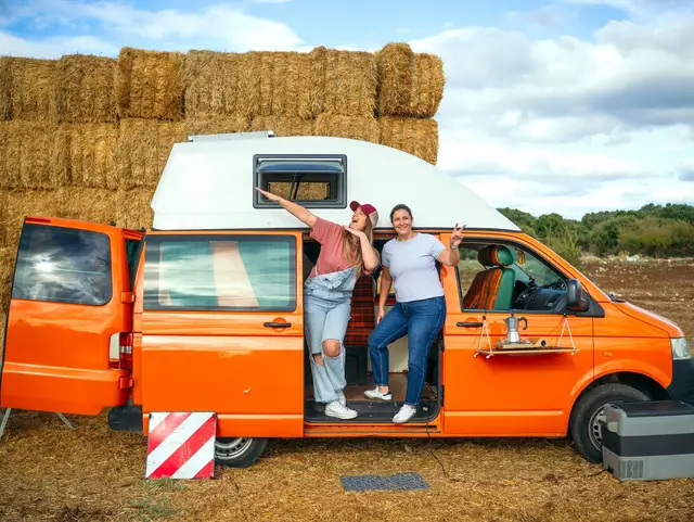 - © karrastock, adobe stock Zwei Frauen vor ihrem Van beim Camping auf dem Land