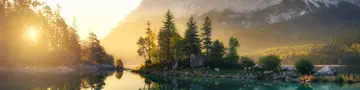 Idyllischer See bei Sonnenaufgang, ein malerisches Panorama mit majestätischen Bergen und dem goldenen Sonnenlicht, das hinter den Bäumen hereinscheint