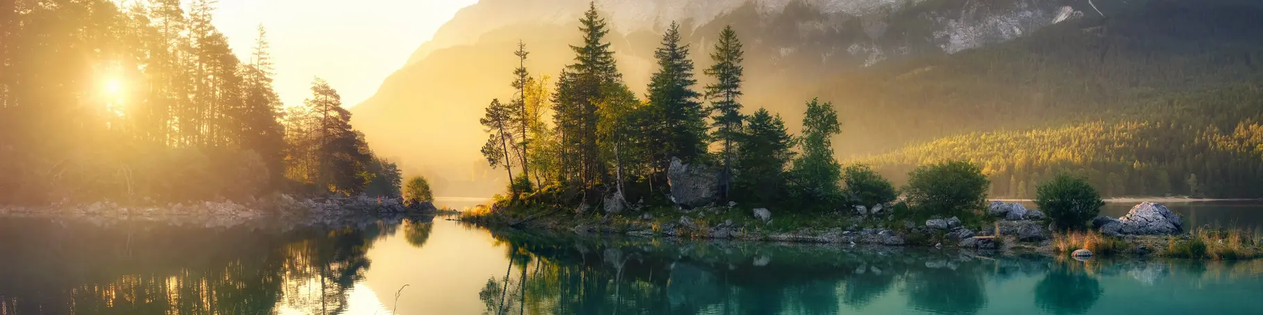 Idyllischer See bei Sonnenaufgang, ein malerisches Panorama mit majestätischen Bergen und dem goldenen Sonnenlicht, das hinter den Bäumen hereinscheint