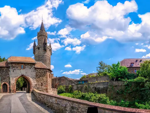 Historisches Burgtor der Burg Friedberg mit dem hohen Adolfsturm, mittelalterlichen Steinmauern und einer Zufahrtsbrücke.