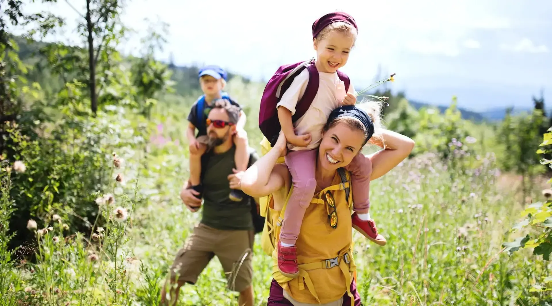 Vorderansicht einer Familie mit kleinen Kindern beim Wandern im Freien in der sommerlichen Natur.