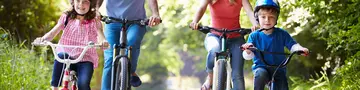 Familie mit 2 Klindern radelt auf einem Feldweg im Wald