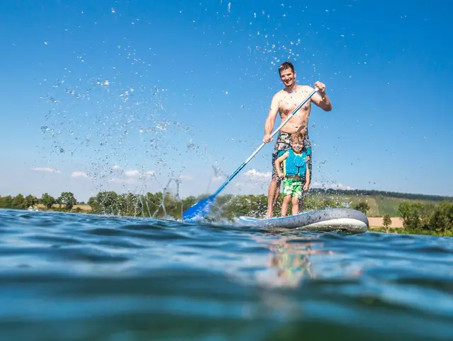 Vater und Sohn haben Spaß beim Standup-paddling auf dem See
