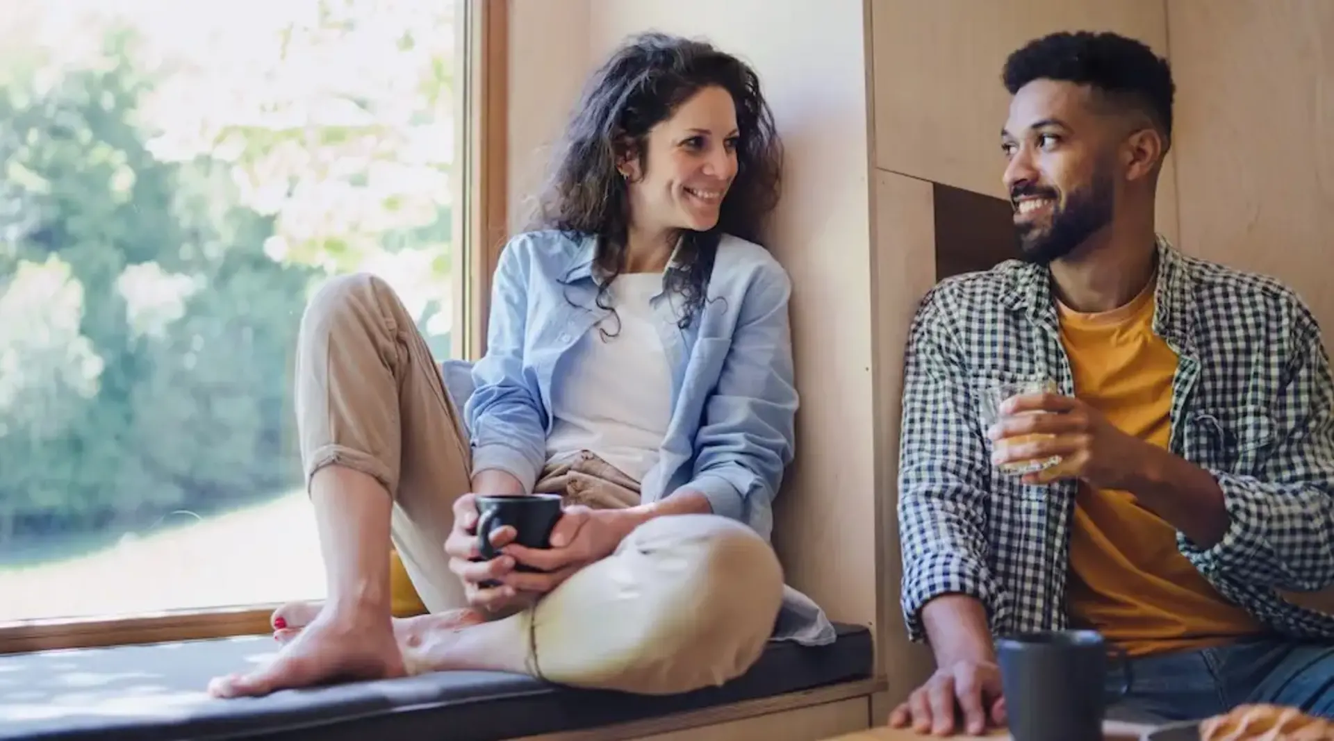 Paar sitzt gemütlich am Fenster und genießt eine entspannte Zeit zu zweit