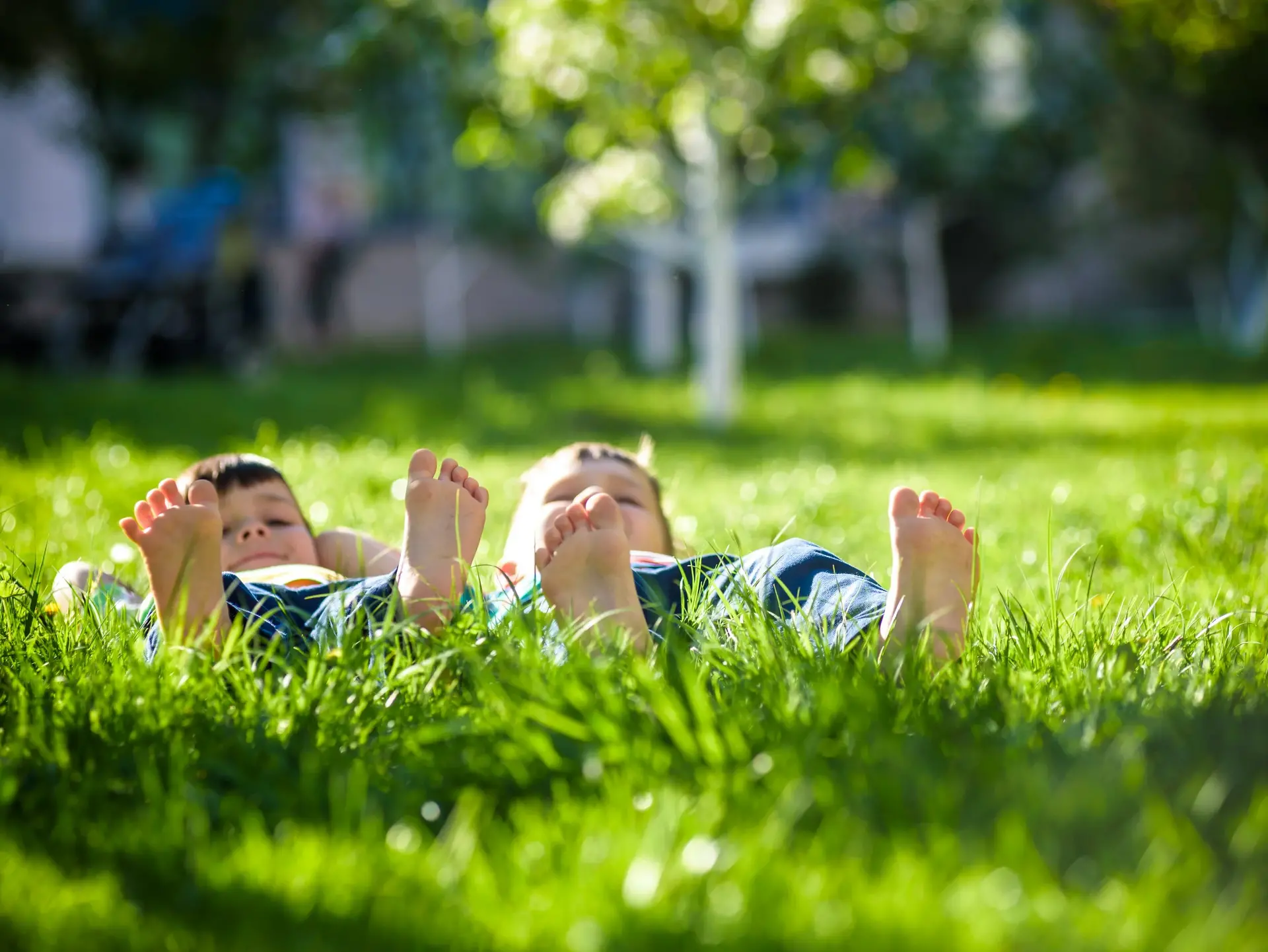 Kinder liegen mit nackten Füßen im Gras - © pahis, Adobe Stock Zwei Jungen liegen auf dem Rücken mit nackten Füßen auf einer Wiese im Gras