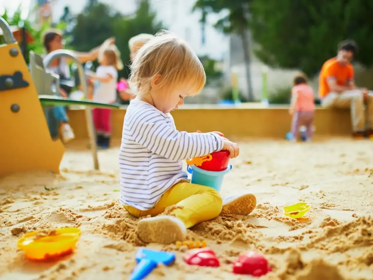 Unbeschwertes Spielen im Freien – Urlaub auf dem Land für Kinder - © Ekaterina Pokrovsky, adobe stock Kleinkind sitzt im Sand und spielt mit Sandförmchen auf einem Spielplatz